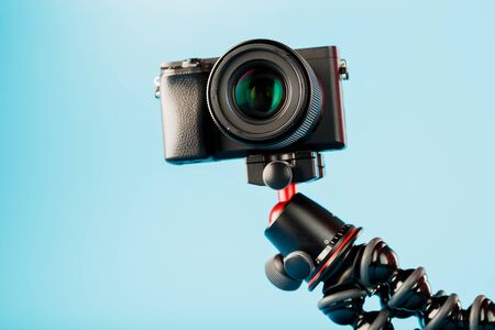 Professional camera on a tripod, on a blue background. Record videos and photos for your blog or report. Free space, isolated.の写真素材