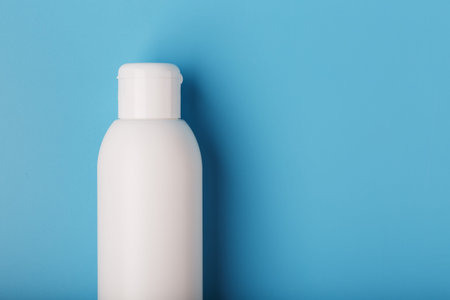 White bottle of cream on a blue background with space for text. Free space for text. The view from...