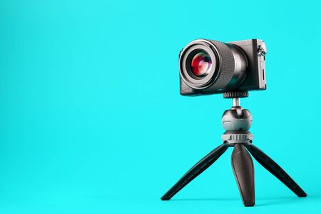 Professional camera on a tripod, on a blue background. Record videos and photos for your blog or report. Free space, isolated.の写真素材