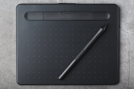 Graphic tablet with a stylus on a dark textural background, top view. Gadget for working as a...