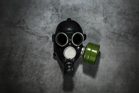 Gas mask on a black stone background with a green filter cartridge. Post-apocalyptic concept. Free space, top view.の写真素材