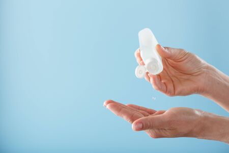 A bottle of Disinfectant gel in your hands on a blue background. Antiseptic treatment of hands from bacteria Sanitizer. Free space, isolate.の写真素材