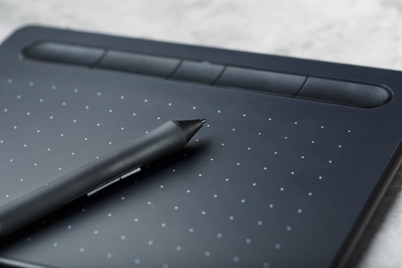 Pen with a graphic tablet in the hands of the designer, close-up. Gadget for art and work. Macro