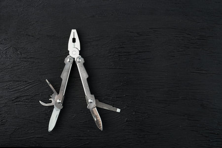 Multi-functional tool on a black textural background. Free space