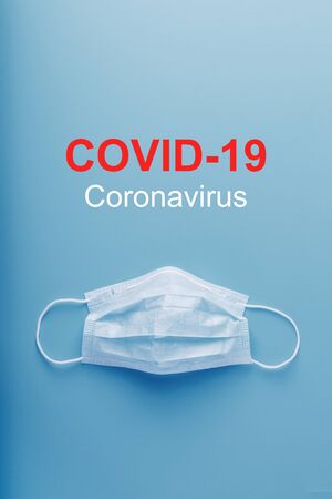 Medical masks for protection against dangerous coronavirus infection with the inscription COVID-19. Lack of protective face masks in the pharmacy. Isolate on a blue backgroundの写真素材