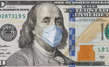 A 100-dollar bill with a face mask by Benjamin Franklin from the COVID-19 Coronavirus in the United States. The COVID virus outbreak is affecting the global stock market and economy. The concept of the Financial crisis and pandemics.の写真素材