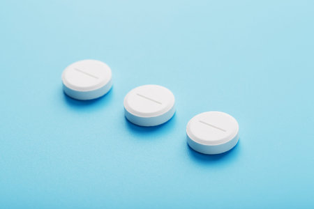 Round medicinal tablets lie in a row on a blue background, isolate. the view from the top, place for...