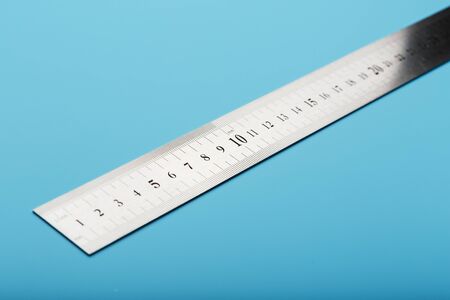 A metal ruler with a scale on a blue background is a superscape with a copy of the space for your text. Isolateの写真素材