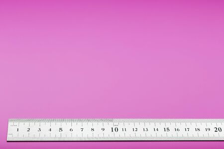 A metal ruler with a scale on a pink background is a superscape with a copy of the space for your text. Isolateの写真素材