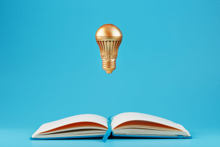 A Golden light bulb in levitation from an open notebook on a blue background. Concept of the idea. Minimalismの写真素材
