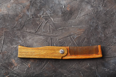 Wooden sandalwood comb on a black textured background. Hair care.の写真素材