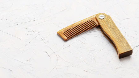 Wooden Sandalwood comb folding on a white textured background. Hair care. Isolate.の写真素材