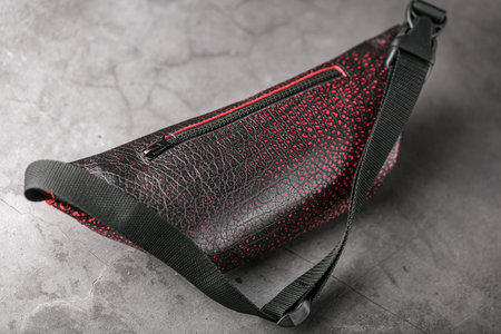 Bag on the belt of textured leather in Bordeaux colour , banana on a gray background. Handmade