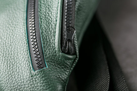 Belt bag made of dark green textured leather, banana on a gray background. Handmade