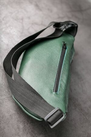 Belt bag made of dark green textured leather, banana on a gray background. Handmadeの写真素材