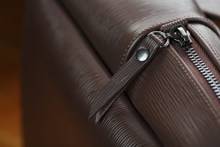 Close-up of the elements of the bag, backpack made of genuine leather with belt buckles and locks. Leather backpack or satchel made of brown leather on a wooden background. Handmade, Studio light.の写真素材