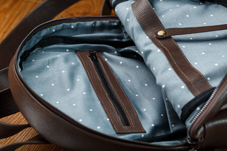 Open empty bag made of handmade genuine leather with elements of locks on a wooden background. Close...