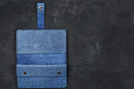 Blue leather wallet on a black textured background. Handmade work