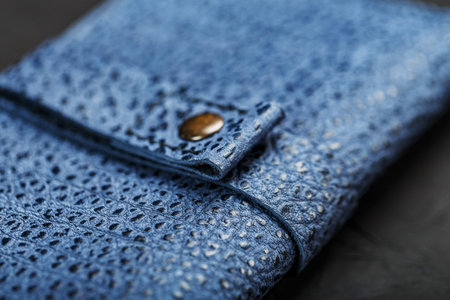 Blue leather wallet on a black textured background. Handmade work
