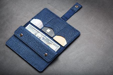 Blue purse with banknotes and credit cards on a black background. Handicraft. Business and Finance