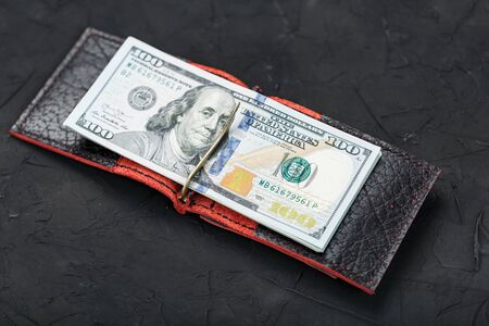 One hundred dollars in a red purse on a black background. Handworkの写真素材