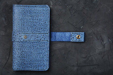 Blue leather wallet on a black textured background. Handmade work