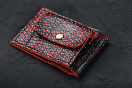 Red and black leather wallet on a black background. Handmade, wallet for money and credit cards.