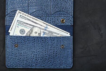 Purse of blue color from genuine leather with new one hundred dollar bills on a black background. Handicraft. Business and Financeの写真素材