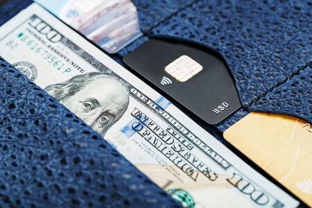 Leather Partman in blue with one hundred dollar bills and electronic credit cards on a black background. Handicraft. Business and Financeの写真素材