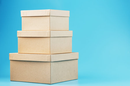 Cardboard boxes in the shape of a pyramid on a blue background. Courier delivery of orders. Fast and...
