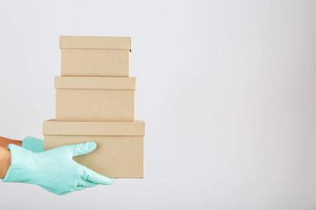 Sending cardboard boxes in the hands of a courier in rubber gloves. Online stores and Secure Express...