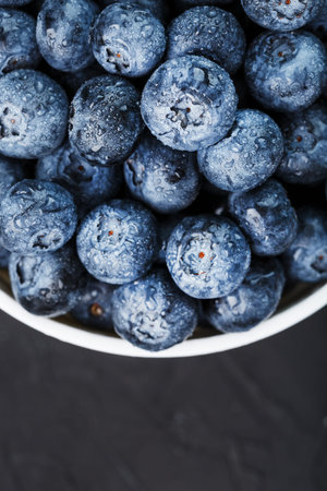 Blueberries in a white Cup on a black textured background. Juicy and ripe forest berry, healthy Food...