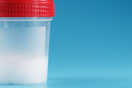 A container for biomaterials with sperm analysis and a red lid on a blue background. The concept of...