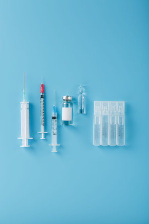A set of medical syringes and ampoules with medicines and vaccines in a row on a blue background. Research of medicines for flu, measles, vaccine disease, pandemic. The view from the top, vertical frameの写真素材