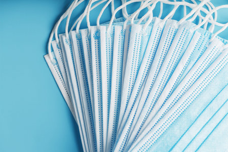 Medical protective masks on a blue background are stacked. Protection against disease