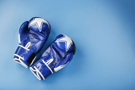 A pair of leather Boxing gloves on a blue background, free space. The concept of fighting and fighting with difficulties.の写真素材