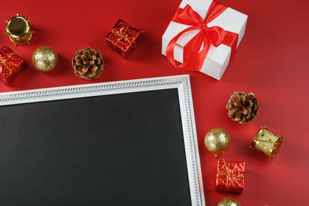 Photo frame with free black space around Christmas decorations and gifts on a red background. Top view, free space for textの写真素材