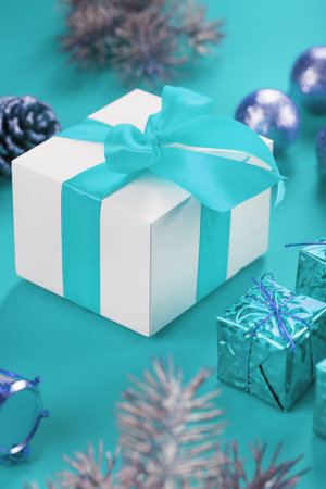 Christmas gift in the form of a white box with a blue bow on a blue background around Christmas decorations. New year's composition of the holiday.の写真素材