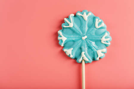 Blue Lollipop in the shape of a snowflake on a pink background. Sweet sugar Lollipop. Minimal flat flat composition, free spaceの写真素材