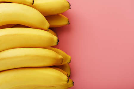 Fresh bunch of yellow bananas isolated on a pink background. Minimalistic concept. Free spaceの写真素材