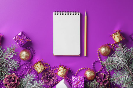 Clean white notepad with pencil around Christmas decorations on purple background. Planning, wish...