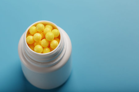 Vitamins are yellow in a white jar on a blue-blue background. Dragee Vitamin C. the Concept of health.の写真素材