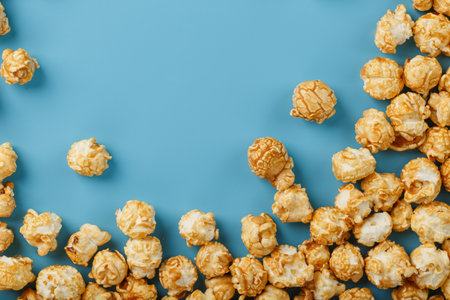 Popcorn is scattered on a blue background, in the form of a frame. Yummy for the filming of movies, TV series, cartoons. Free space, top viewの写真素材
