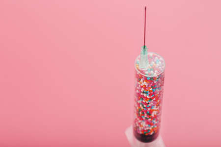 Medical Syringe filled with colorful balloons on a pink background with free space. Conceptual medical vaccine development.の写真素材