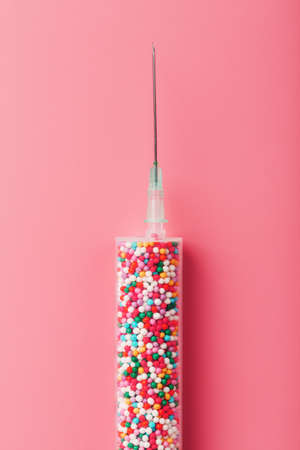 Medical Syringe filled with colorful balloons on a pink background with free space. Conceptual medical vaccine development.の写真素材