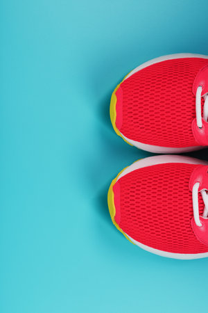 Pink sports sneakers for running on a blue background with free space. Top view, minimalistic conceptの写真素材