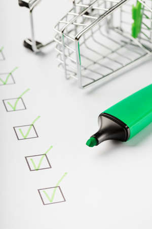 Supermarket Cart and Green Marker Marked on the Checklist Sheet. Shopping checklist completed task concept.の写真素材
