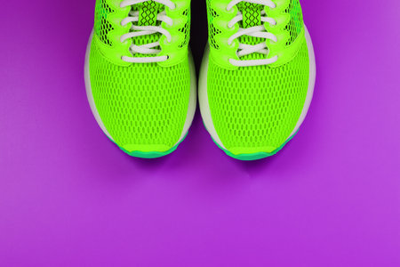 Green running shoes on a purple background. Top view, free spaceの写真素材