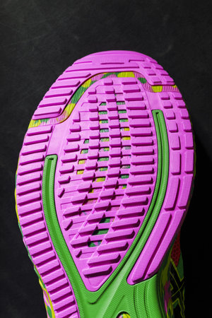 Textured pink sole of sports running shoes on a black background. Crazy modern colors. Sporty style,...