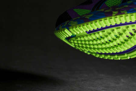 A sporty running shoe with a textured green sole on a black background. Bright colors modern colors. Sporty style, close-upの写真素材